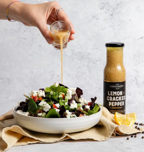 Lemon and Cracked Black Pepper salad dressing being poured over a feta salad